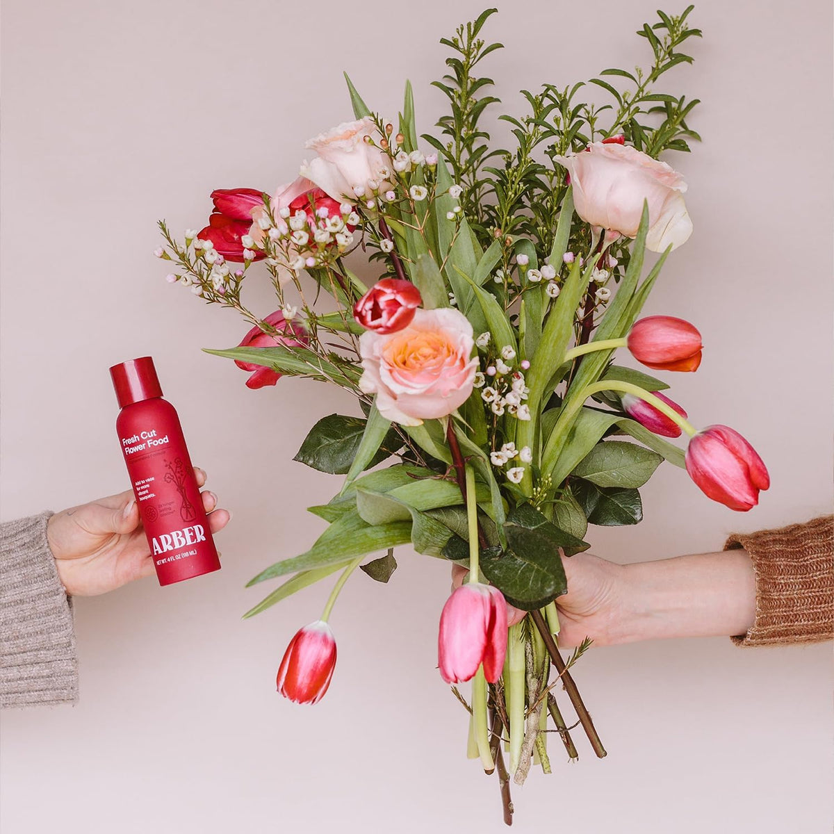 ARBER floral food bottle beside lush bouquet during setup