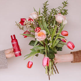 ARBER floral food bottle beside lush bouquet during setup