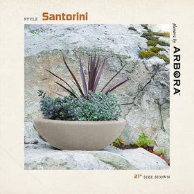 Cream finish ARBORA Santorini Bowl sits among lush plants in a garden.