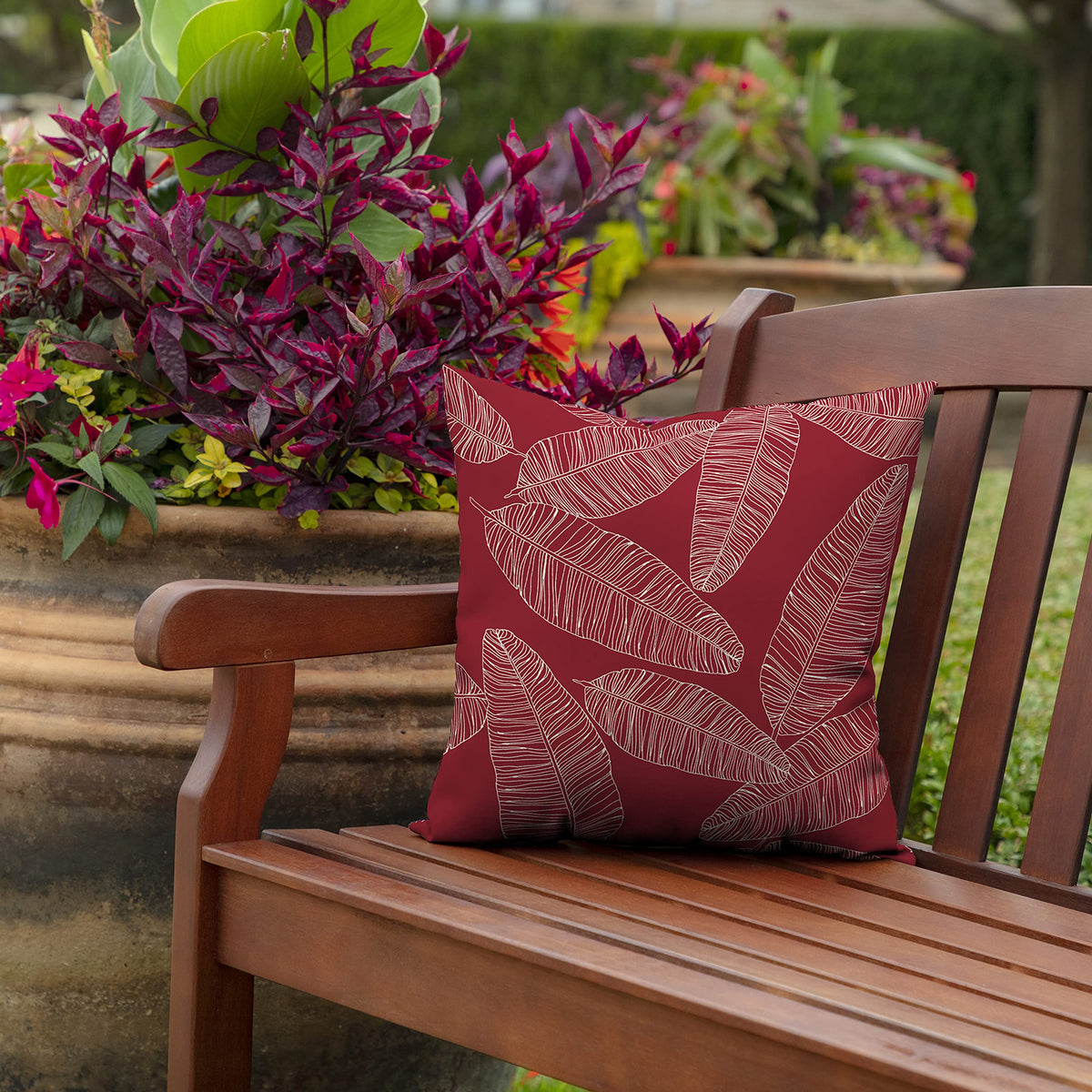 Arden Selections pillow on a chair with red leaf palm pattern for sunlit spaces