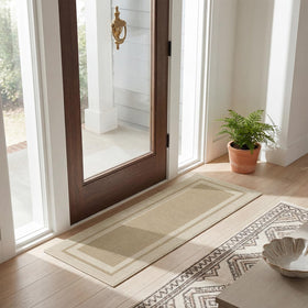 Artoid Mode beige doormat being rinsed under a hose, showcasing quick-clean maintenance.