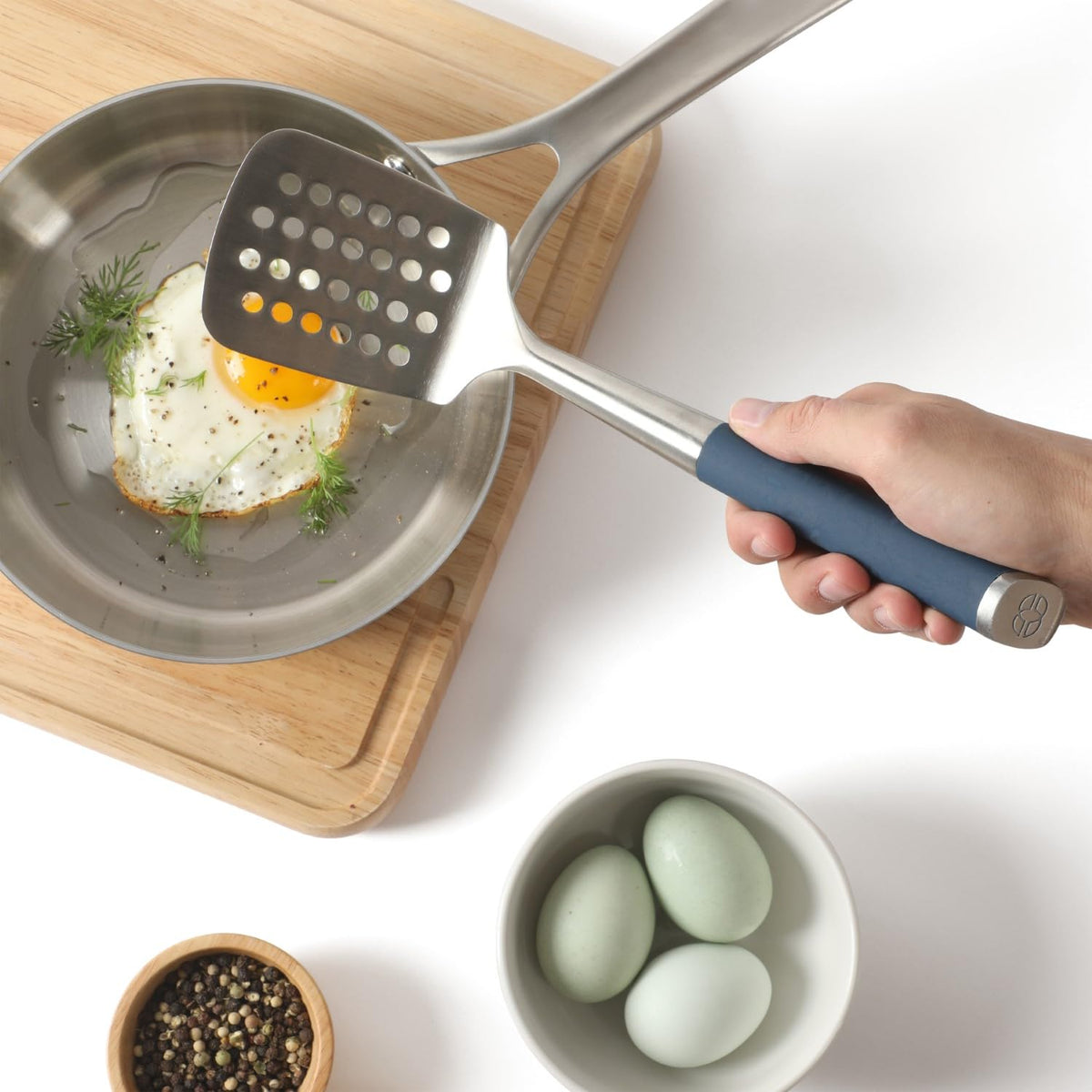 Calphalon Edge slotted turner with non-slip navy handle for comfortable grip.