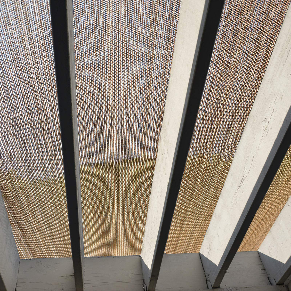 Fence4ever brown shade fabric roll edge being cut to fit a custom space