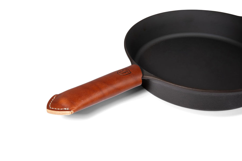 Field Company brown leather handle cover on a cast iron skillet providing secure heat protection.