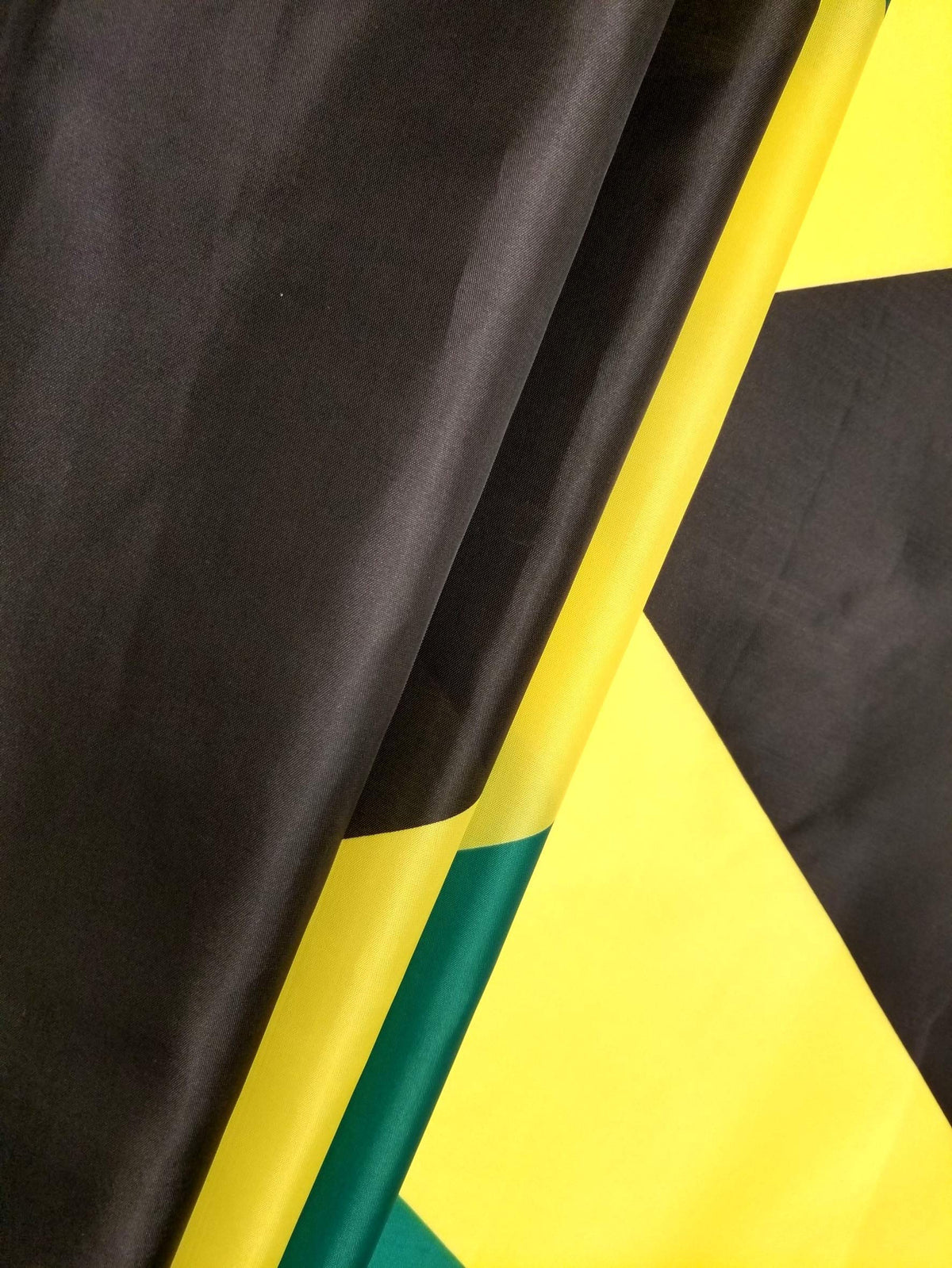 High Supply Jamaican flag close-up brass grommets and stitching detail.