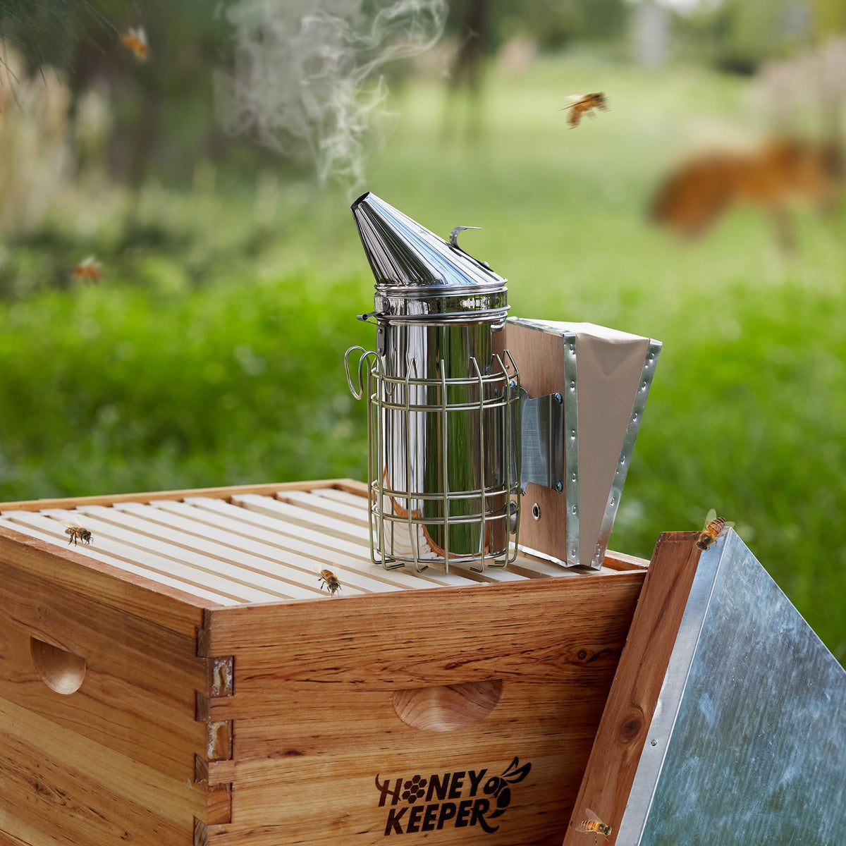 Honey Keeper smoker with heat shield protecting hands during inspections