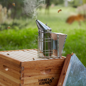 Honey Keeper smoker with heat shield protecting hands during inspections