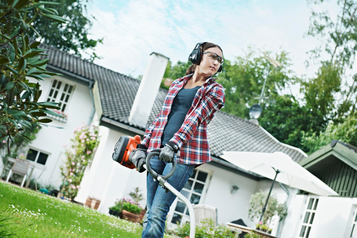 Husqvarna 122C weed wacker in action along landscaping borders.