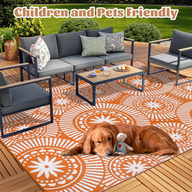 Ileading outdoor rug on a deck showing two-sided geometric design in orange.
