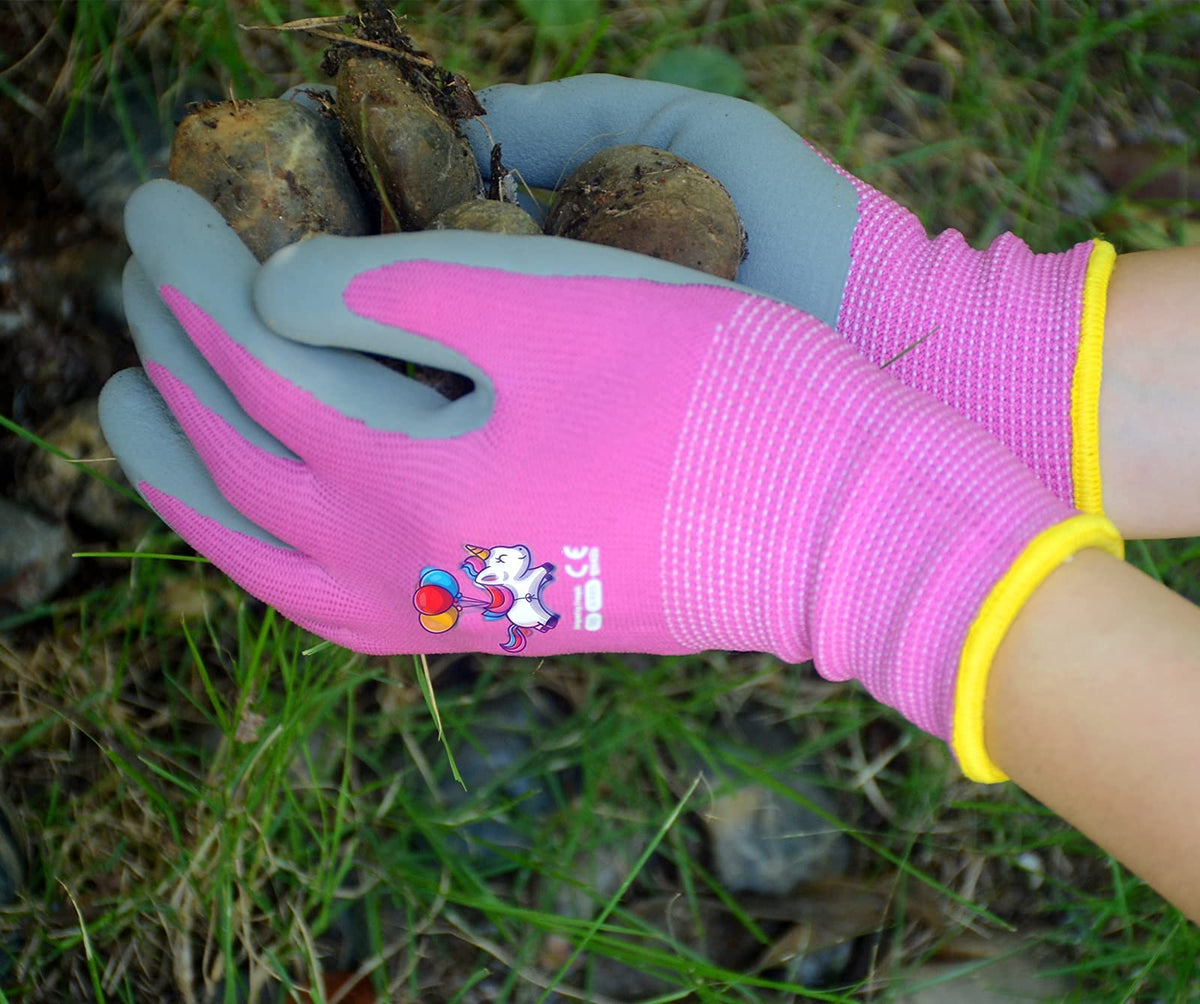 KDK pink unicorn gloves worn by a child gardening outdoors for protection.