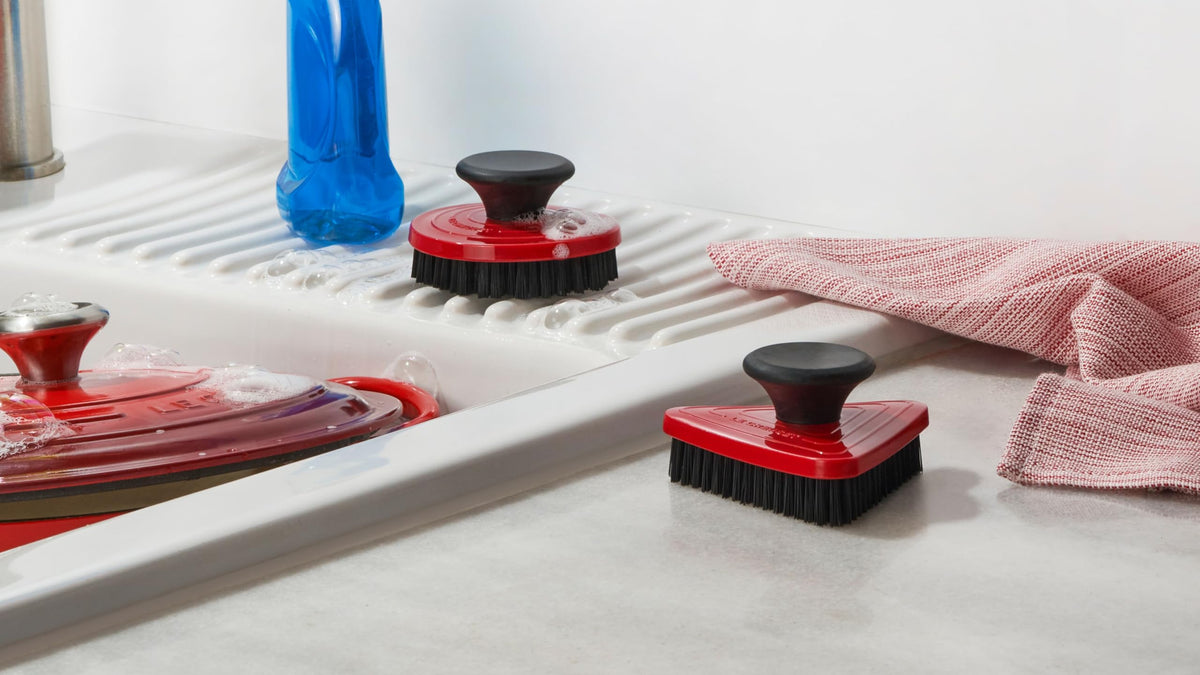 Le Creuset triangular cleaning brush reaches tight corners for precise, thorough pan cleaning