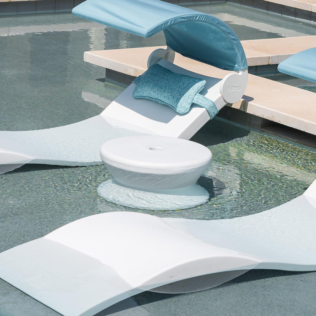 Ledge Lounger white table on pool ledge showcases rust-free, no-maintenance design.