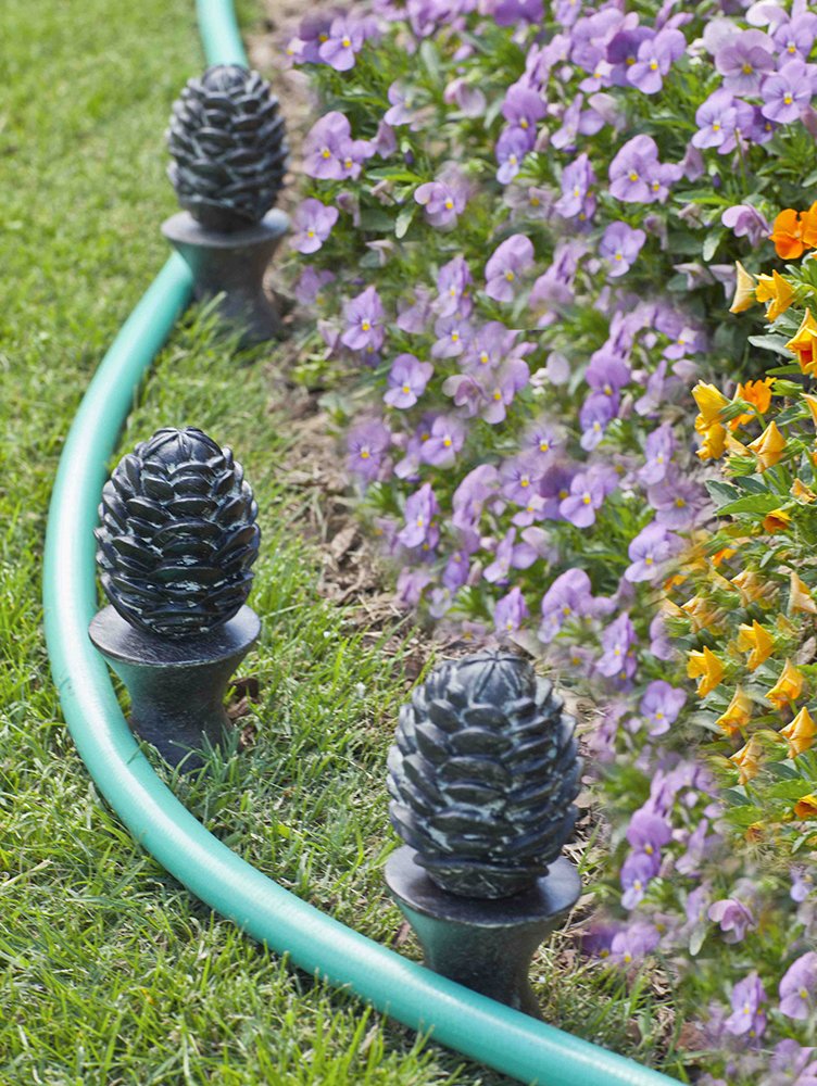 Liberty Garden 615 bronze hose guide installed in garden to reduce hose drag.
