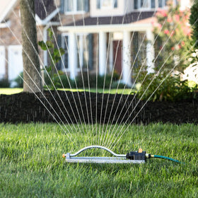 Melnor sprinkler watering a lawn and flower beds with uniform coverage