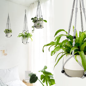 Mkono macrame indoor/outdoor hanger displayed with plant on balcony.