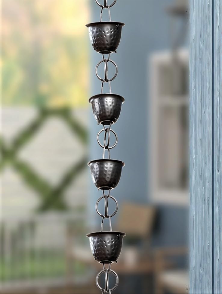 Monarch Rain Chains installed along a gutter with outdoor scenery in the background.