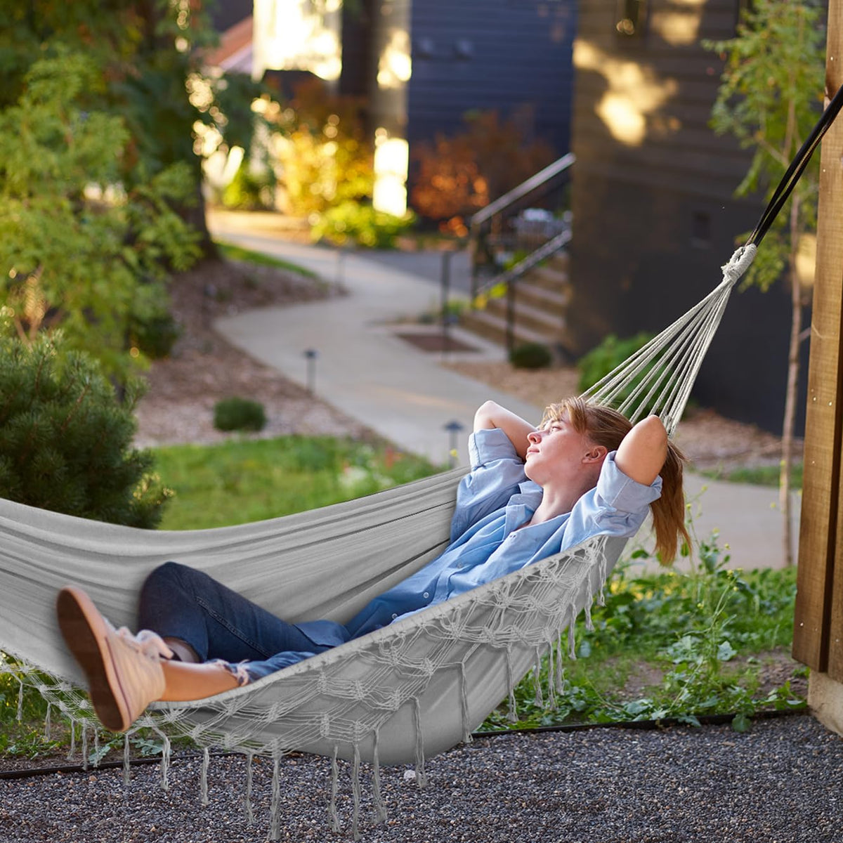 MOSFiATA hammock hung between trees in a garden for lounging.