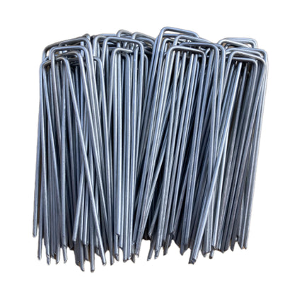 MPHKFDE 6-inch galvanized garden stake penetrating soil to secure landscape fabric.