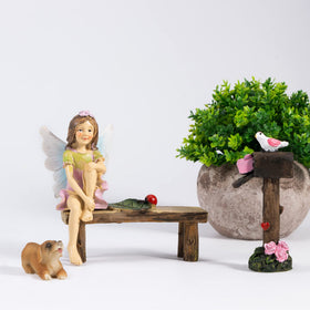 MUAMAX fairy figurines on bench create a cozy garden scene.