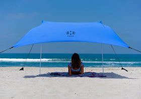 Neso portable beach tent with sand anchor for secure shoreline setup.