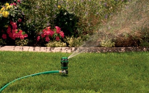 Orbit tripod-base sprinkler showing stable setup for uneven turf.
