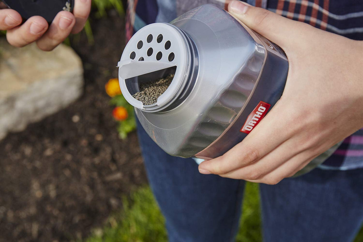 Close-up of granules being applied around a garden bed for protection