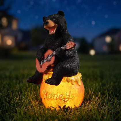PETAFLOP solar garden statue bear holding honey jar glows at night for warm outdoor ambiance.