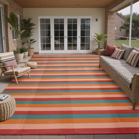 PureCozy outdoor rug on beach and patio setup with vibrant stripes.