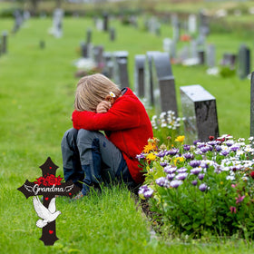 Rngmsi cross memorial plaque stands upright in a cemetery lawn.