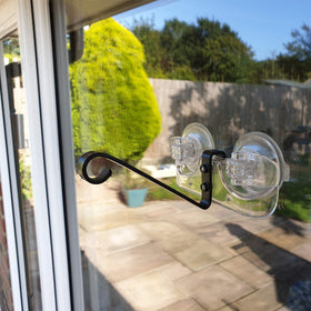Roamwild feeder bracket attached to window glass with visiting birds nearby