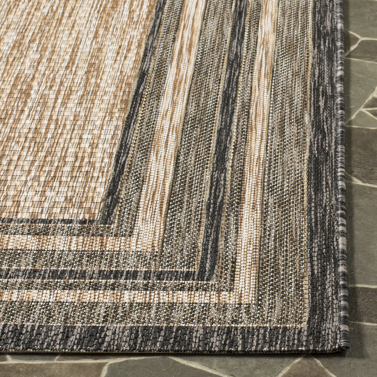 Safavieh Courtyard rug being rinsed with a garden hose, showing easy cleaning.