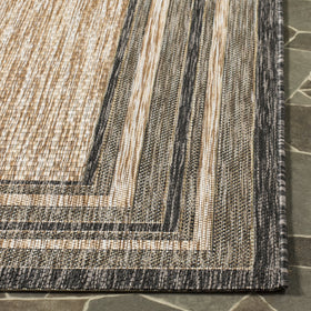 Safavieh Courtyard rug being rinsed with a garden hose, showing easy cleaning.
