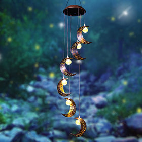 Tryme windchimes hung on a tree sway with soft light