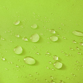 VAKADO green pillow cover on garden bench, keeps cushions clean in outdoor spaces.