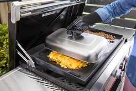 Weber Griddle Extra-Large Basting Dome with heat-resistant handle near paninis for easy flipping.