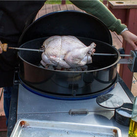 Weber rotisserie kit installed on kettle showing forks for even roasting