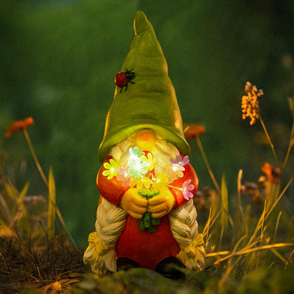 WONDHOME solar garden gnome lady statue with flowers glows at night for ambient outdoor lighting.