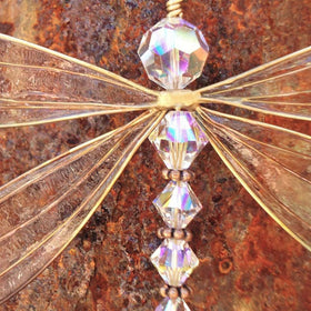 XinTX Dragonfly crystal suncatcher on a bedroom windowsill with soft light